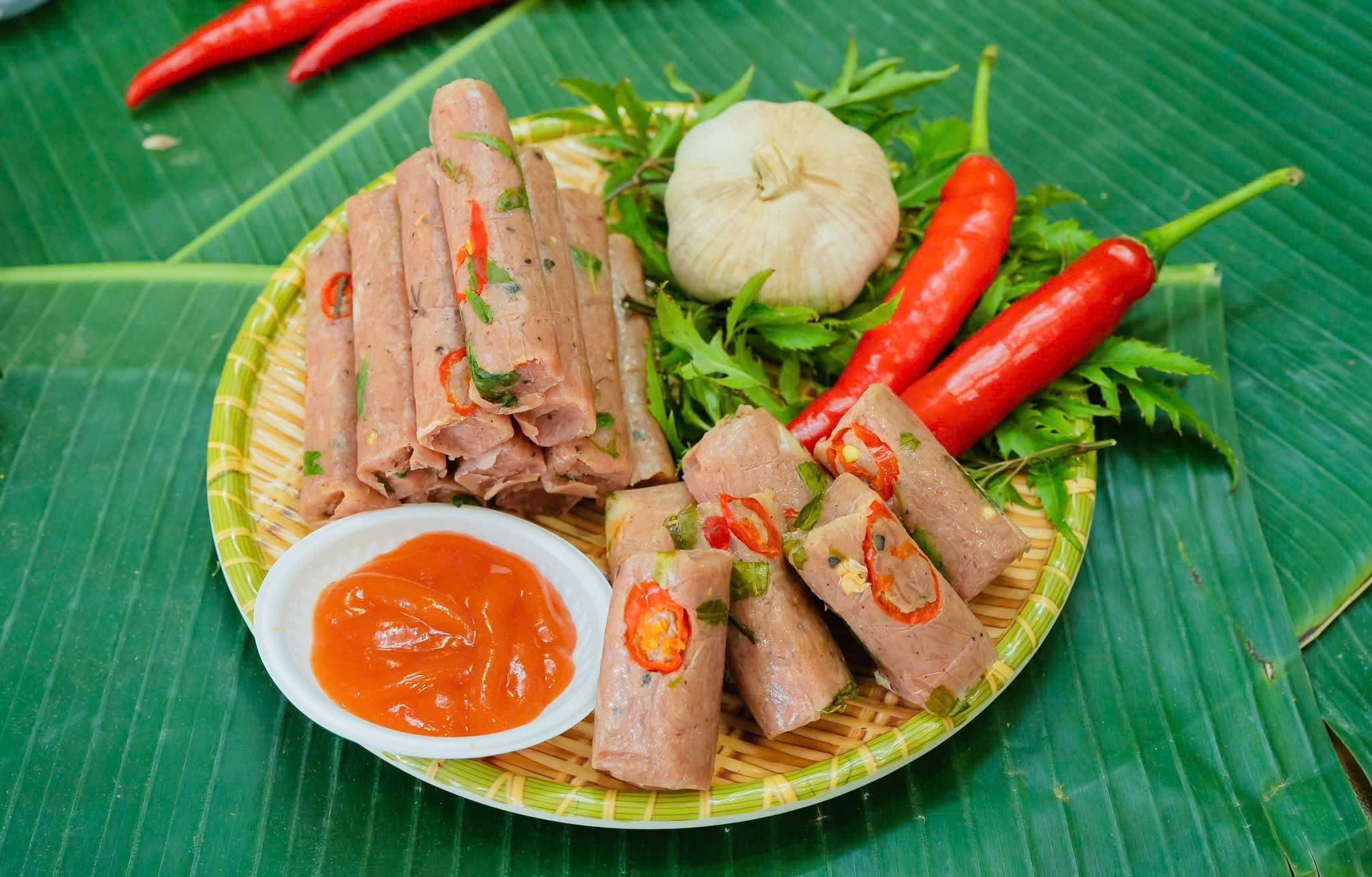 Nem chua Xứ Thanh bày trên mẹt lá chuối cùng tỏi, ớt và tương ớt